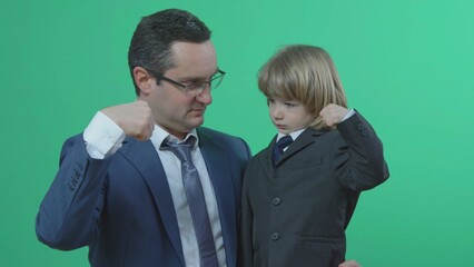 Father and son with suit and tie show muscle, green background