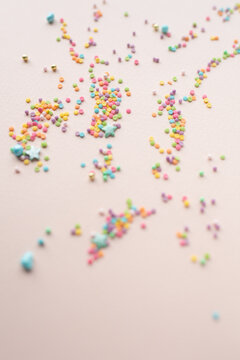 colored confetti on a beige background, pastel colors, festive background, festive serpentine, birthday party