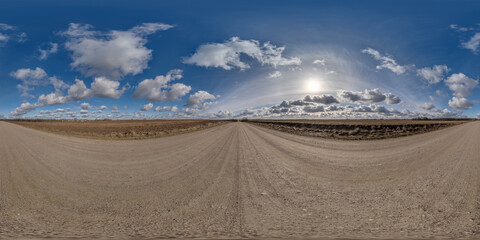 spherical 360 hdri panorama on gravel road with clouds on blue sky with halo in equirectangular...