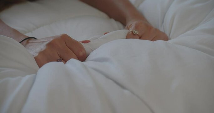 Female Hands Grabbing Bedsheet While Making Love In The Bedroom. closeup