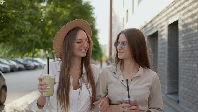 Two young tourists beautiful woman girl female hipster friends in summer clothes walking meeting laughing drinking fresh cocktail In street outdoor Friendship travel having fun happiness freedom love 