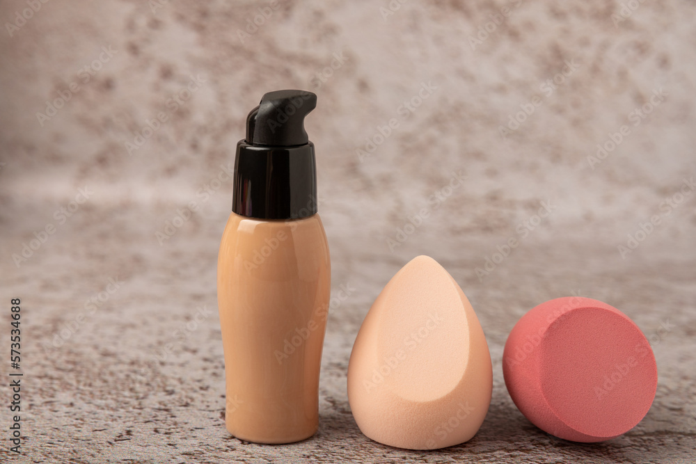 Wall mural Liquid foundation for makeup and sponge blender for makeup. Foundation beauty face makeup application, perfect makeup tool. Beauty blender,bb cream or concealer on marble texture background.