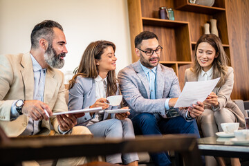 Teamwork. Team discussing something and smiling while sitting at the modern business lounge.