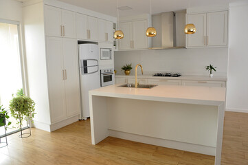 Fototapeta na wymiar cozinha branca de quartzo linda luxuosa com detalhes dourados 