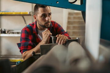 The young craftsman works on a large printing machine in the company.