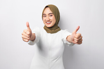 Beautiful smiling friendly young Arabian Asian Muslim woman wearing hijab showing thumb up gesture isolated on white background. People religious lifestyle concept