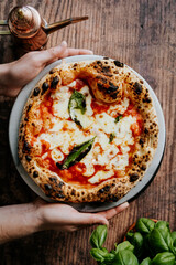 Hands Holding a 12' Long Fermented sourdough pizza Margherita baked in a wood-fired pizza oven.