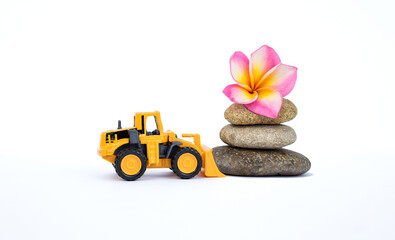 Yellow front loader truck with flower on stone isolate on white background, spring season concept, spa and wellness industry