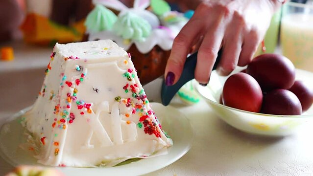 Woman's hand cuts the Cottage cheese easter in home kitchen. Orthodox religion theme.