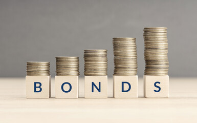 Bonds increasing concept. Text word on wooden blocks with coins stacked in increasing stacks. Copy...