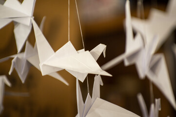 Japanese folded Origami cranes hanging on with strings. Hundreds handmade paper birds isolated with copy space. 1000 thousand crane sculpture topic. Symbol of peace, faith, health, wishes, hope