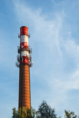 Boiler house chimney. Colorful tower against the clear blue sky. Industrial zone of the city.