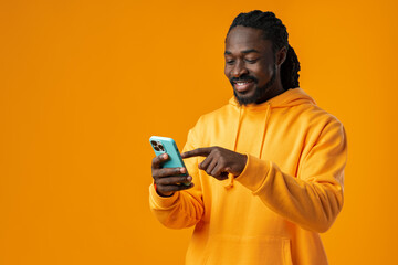 Portrait of handsome african man using his mobile against yellow background