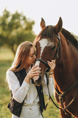 Young beautiful female jockey strokes and hugs the horse's head and prepares for the competition....