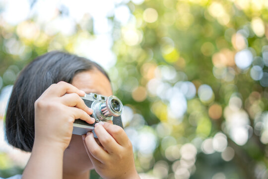 film camera in the hands of a girl taking a picture. Green trees boudoir backdrop.woman taking photos with a camera, selective focus, soft focus.