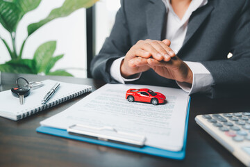 Business woman's hand protecting red toy car on desk. Planning to manage transportation finance costs. Concept of car insurance business, saving buy - sale with tax and loan for new car.