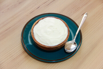 Fototapeta na wymiar White fermented milk yogurt in a decorative brown plate on a wooden background