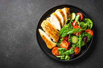 Healthy food plate, keto diet. Green salad with chicken fillet on black table. Top view with copy space.