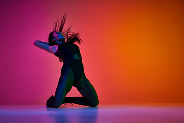 Self-expression through movements. Young woman dancing high heel dance style over gradient pink...
