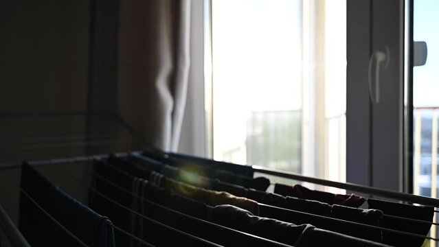 Person hanging clothes to expandable drying rack standing near window