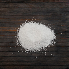 Fototapeta na wymiar Pile of Sodium benzoate, sodium salt of benzoic acid on wooden surface, close-up. White crystalline powder, C6H5COONa. Food additive E211, Preservative
