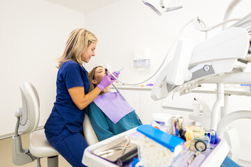 Female dentist working in dental clinic examining patient teeth.