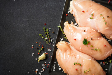 Chicken breast with ingredients for cooking at black background. Top view with copy space.