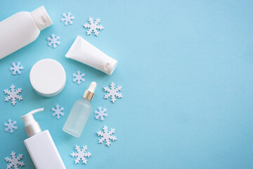 Winter cosmetic with knitting scarf on blue background. Flat lay with copy space.