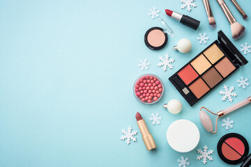 Make up products and christmas decorations on blue background. Holiday shopping. Flat lay image with copy space.