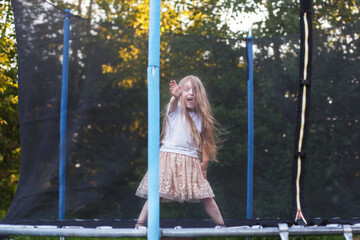 Little child girl jumping on the trampoline in the back yard