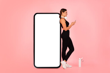 Cool App. Fit Woman Using Smartphone While Leaning On Huge Blank Cellphone