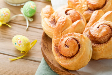 Fototapeta na wymiar Easter breakfast Holliday concept. Easter bunny buns rolls with cinnamon made from yeast dough with orange glaze, easter decorations, colored eggs on old wooden background. Easter Holliday card.