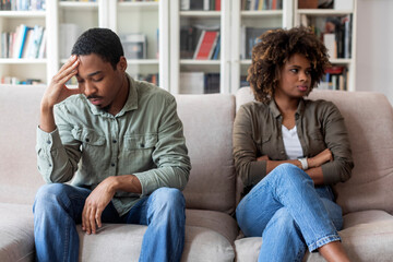 Unhappy black couple sittng on sofa at therapist office