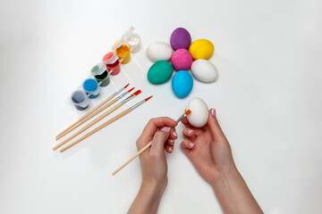 A painted Easter egg an a woman hands. Female painting an Easter egg with a watercolour. Close-up
