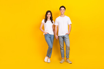 Full length photo of charming sweet husband wife dressed white t-shirts holding hands arms empty space isolated yellow color background