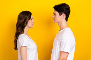 Fototapeta premium Photo of sweet pretty husband wife dressed white t-shirts standing looking each other isolated yellow color background