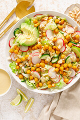 Healthy spring vegan Caesar salad with chickpea, fresh cucumber, radish, avocado and crispy croutons, dressed with garlic sauce.