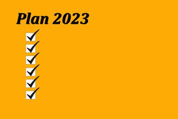 Planning for 2023 on an orange background. Write 2023 in a notepad. New Year's goals. List of goals for 2023. List of business ideas