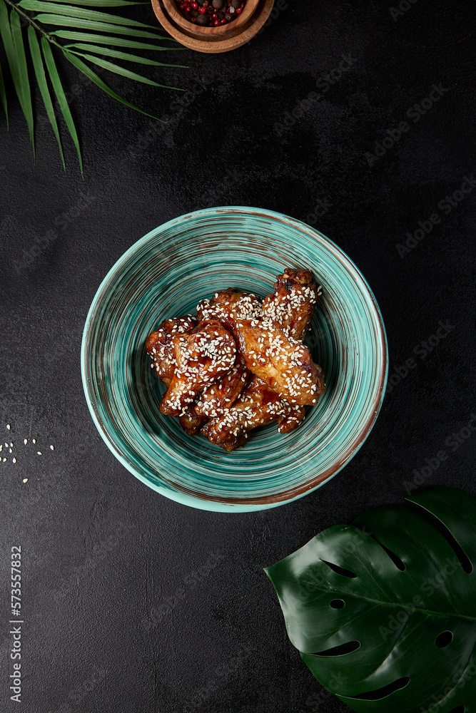 Poster roasted chicken wings in teriyaki sauce with sesame on ceramic bowl. buffalo wings in asian style on