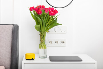 Photo of bedroom interior with useful devices and bouquet of flower