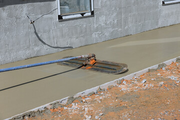 After pouring concrete over wet concrete surface worker plasters floor with trowel using