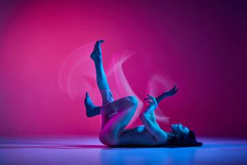 Soul. Young talented artistic woman in bodysuit dancing contemp over gradient pink studio background in neon with mixed lights. Concept of contemporary dance style, art, aesthetics, hobby, creativity