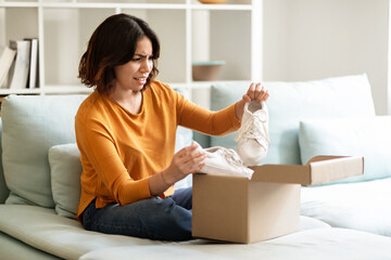 Wrong Parcel. Anxious arab woman taking shoes out of box and frowning