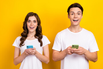 Photo portrait of excited funny addicted new iphone smartphone users typing text internet chat wear...
