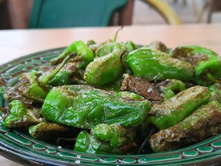 Spanische Pimentos de Padron auf grünem Teller