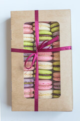 Macaroons in box. French macaroon cake. Sweet macarons or macaroons, flavored cookies are in the paper box on white background. Colorful pink blue yellow green macaron. Sweet macaroons macarons.