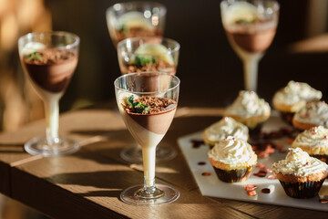 Candy Bar. Delicious sweet buffet with vanilla chocolate mousse desserts and cupcakes with white milk cream on wooden table . Birthday party, anniversary, wedding party at restaurant
