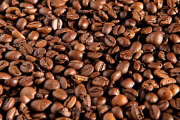 Coffee beans background. Texture of coffee beans close up. Dark brown roasted coffee is spinning. Abundance. Concept for coffee product advertising. Selective Focus. Border design with copy space