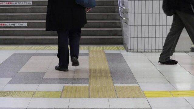 冬の名古屋駅構内の階段を上る通勤客と歩く人々の姿
