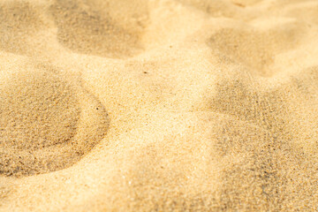Fototapeta na wymiar Close-up of yellow sand on the beach. Small grains of sand on a clean beach. Toned photo with low depth of field.